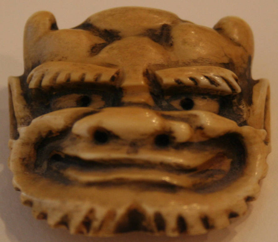 Carved ivory netsuke of a demon mask