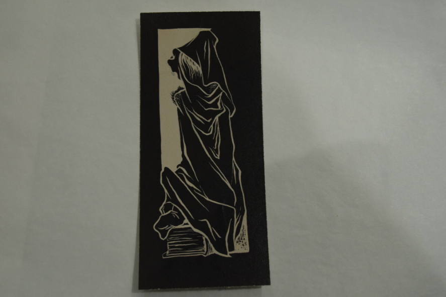 Cloaked figure sitting on book